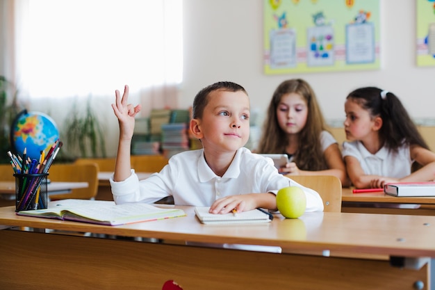 子供は教室で手を上げている