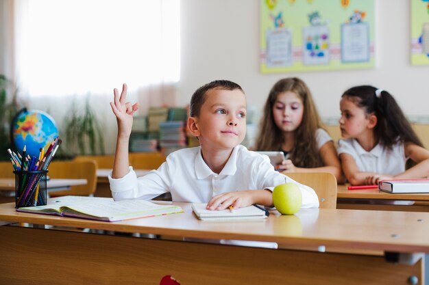 Kid holding hand up in classroom