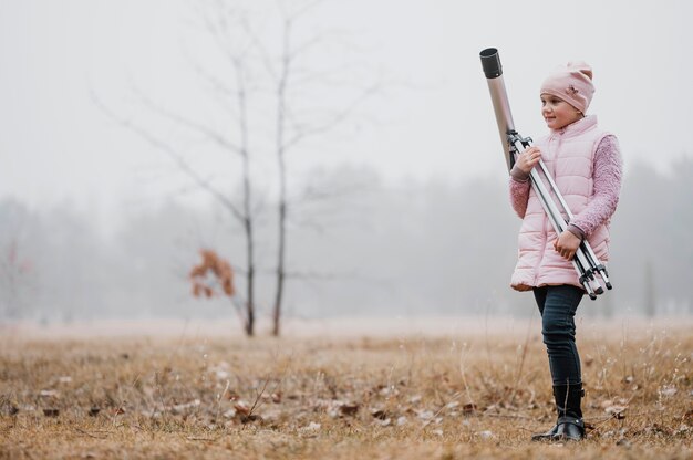 Kid holding a telescope outside with copy space