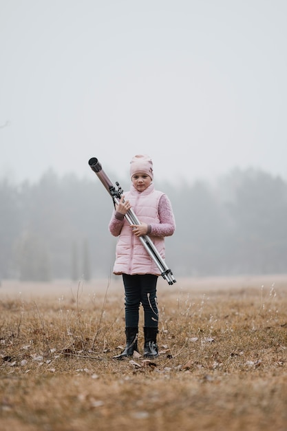 Free photo kid holding a telescope outside