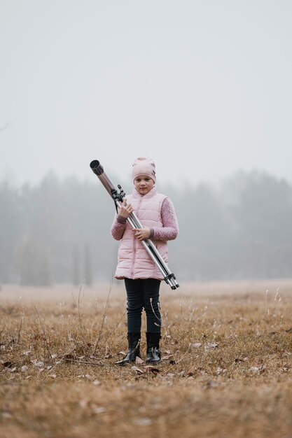 Kid holding a telescope outside