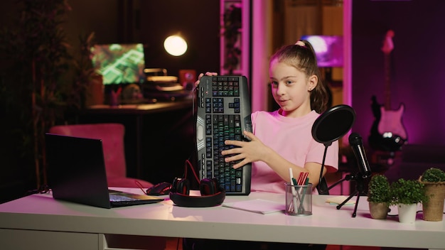 Kid influencer in studio using camera to review gaming keyboard mouse and headphones