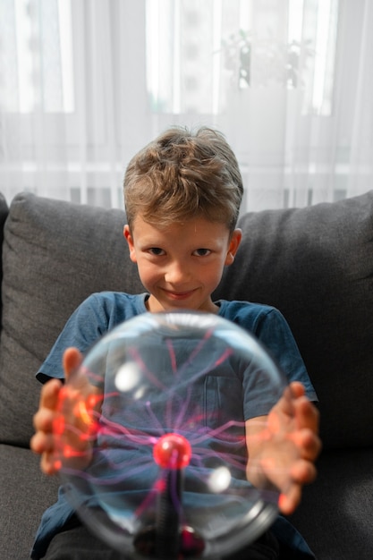 Foto gratuita bambino che interagisce con una palla al plasma