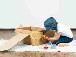 Free photo kid painting cardboard boat