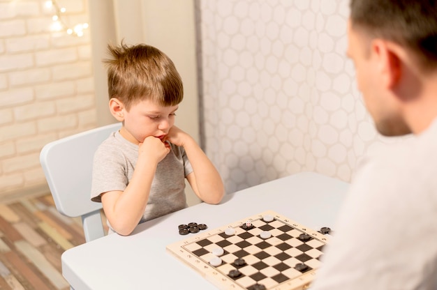 Kid playing chess with father