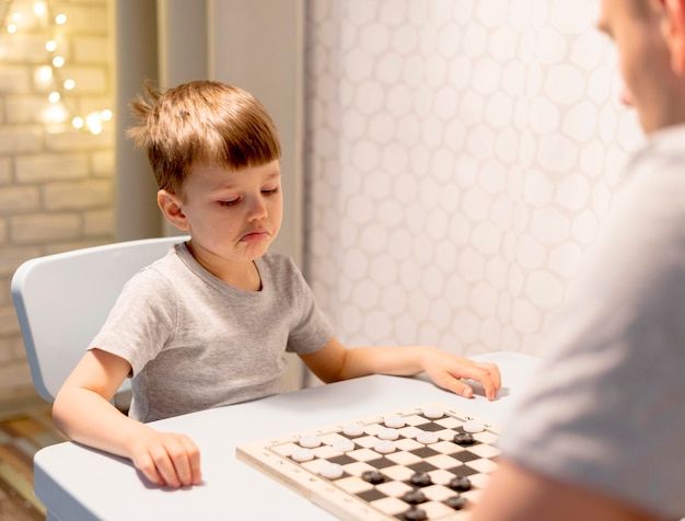 Kid playing chess with man