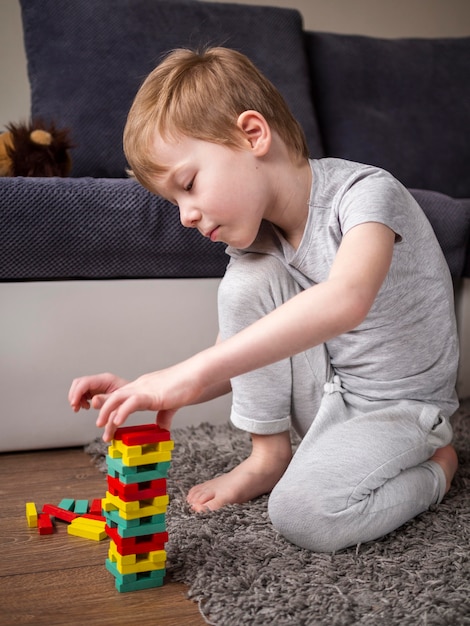 Free photo kid playing with colorful wooden tower game