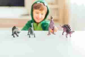 Free photo kid playing with toy dinosaurs