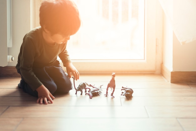 Free photo kid playing with toy dinosaurs