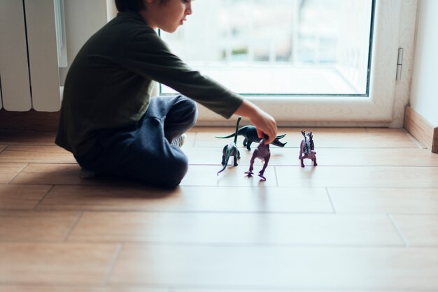 おもちゃの恐竜と遊ぶ子供