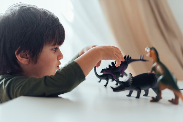 Free photo kid playing with toy dinosaurs