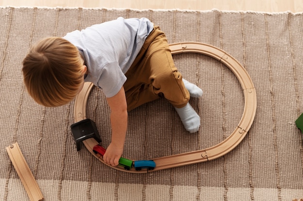 Ребенок играет с деревянным поездом в полный рост