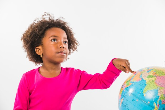 Kid pointing at globe in studio