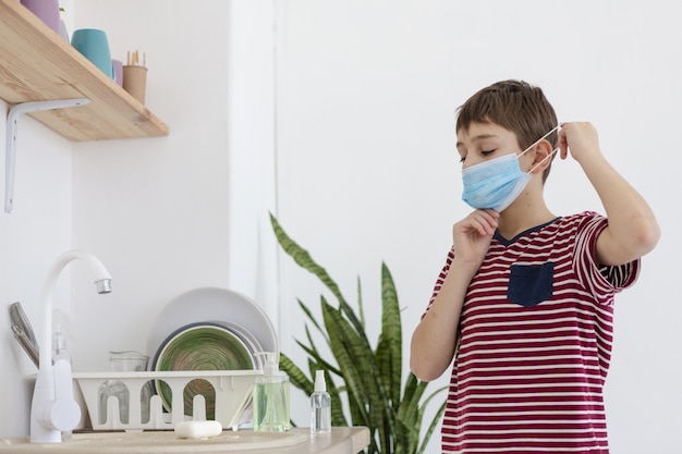 Free photo kid putting on medical mask