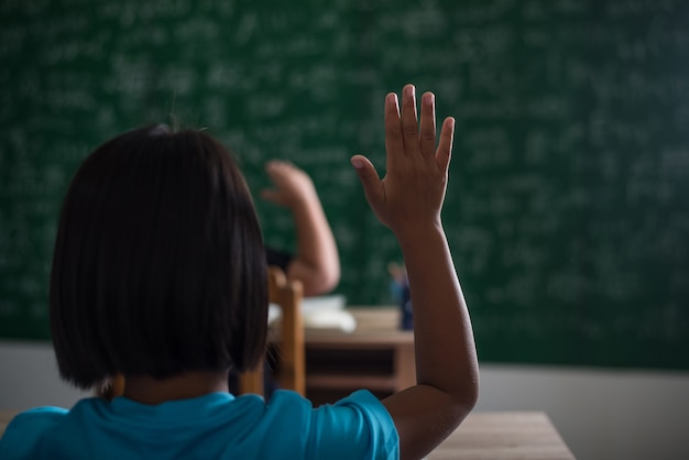 kid raising his hand in classroom 