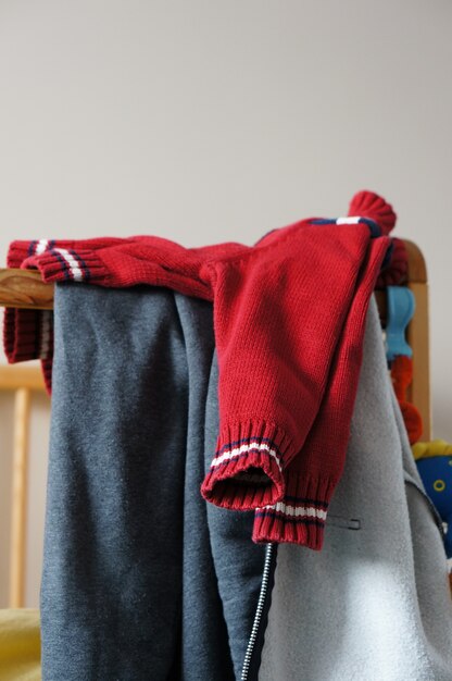ベビーベッドの上の子供の赤いニットセーター