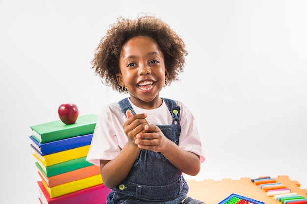 Kid sitting with books and smiling in studio 