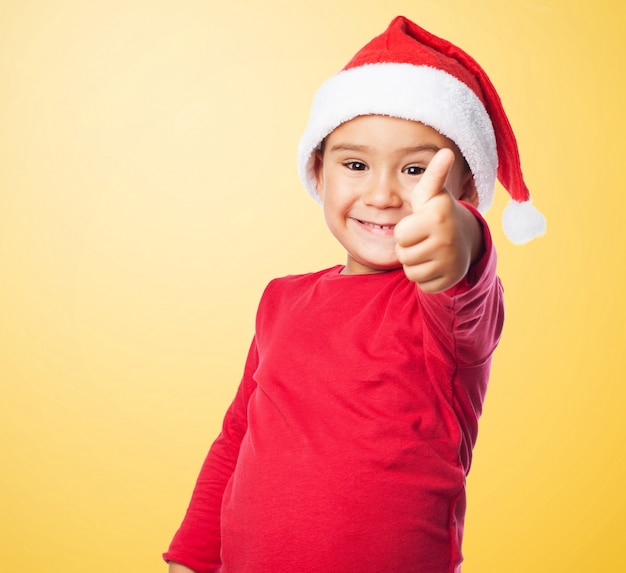 Малыш улыбается с пальца вверх и шляпу Санта Клауса