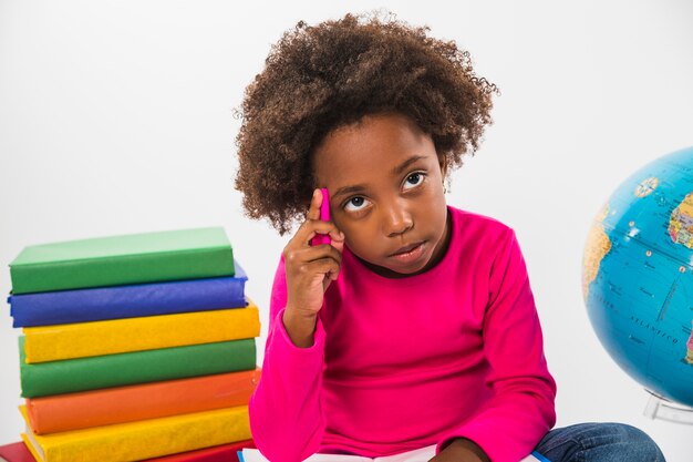 Kid thinking sitting with books in studio