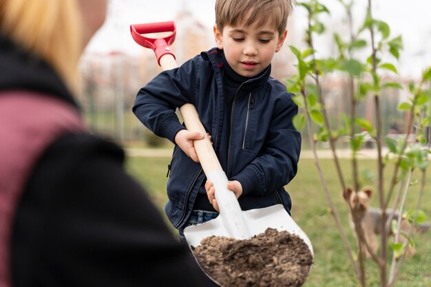 Ребенок пытается посадить дерево на открытом воздухе