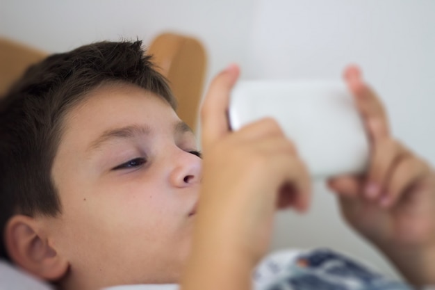 Kid utilizzando un telefono cellulare intelligente e sorridente