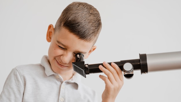 Foto gratuita ragazzo che usa un telescopio in classe