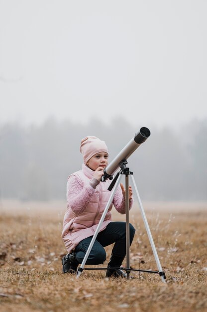 밖에서 망원경을 사용하는 아이