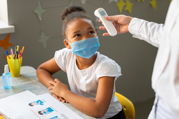 Kid waiting for the teacher to take her temperature