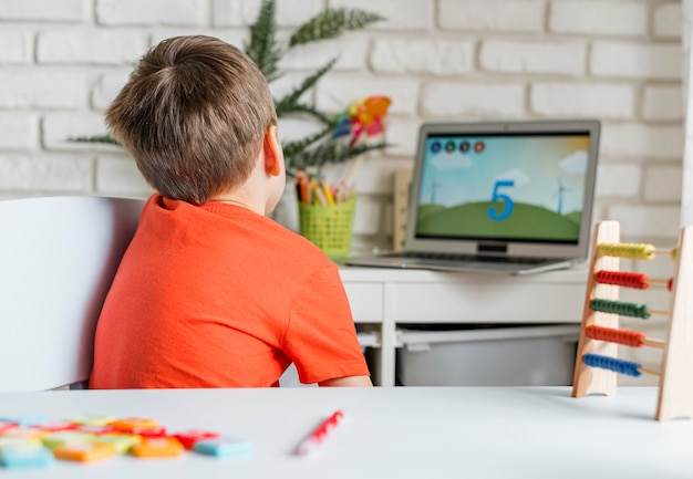 Free photo kid watching video on laptop