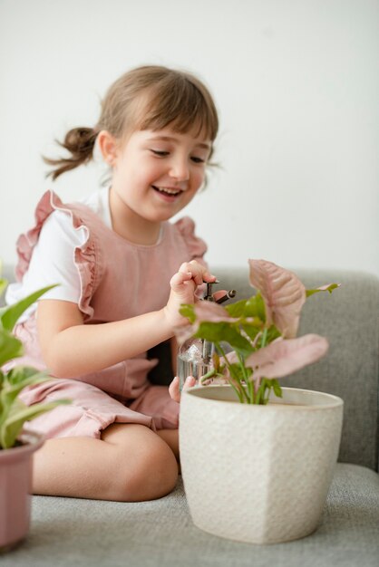 家で鉢植えの植物に水をまく子供