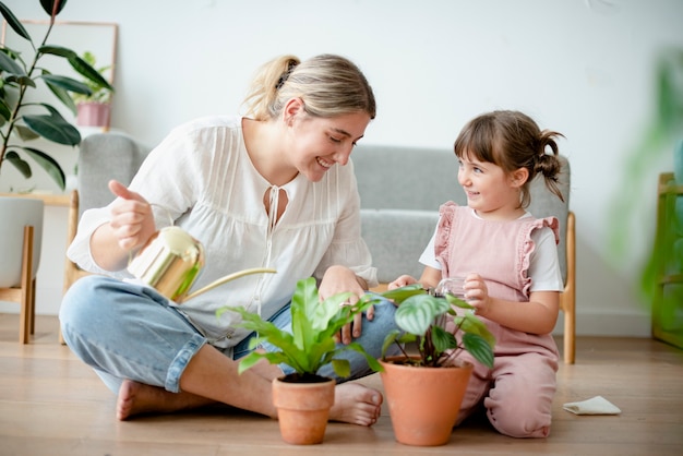 家で鉢植えの植物に水をまく子供