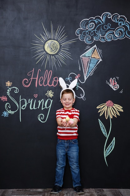 Kid wearing bunny ears and holding heap of easter eggs