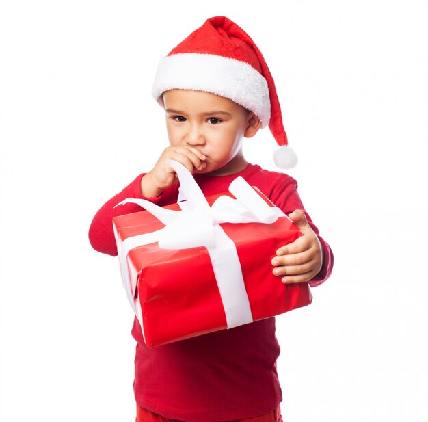 Kid with a gift touching his mouth