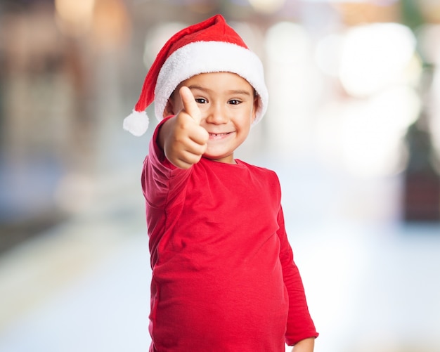 Ребенок с большим пальцем вверх и шляпу Санта Клауса