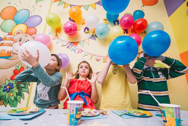 誕生日お祝いの間に風船を吹く子供たち