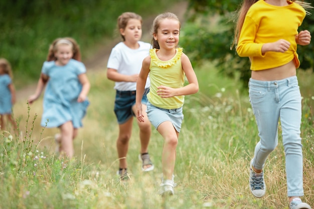 緑の牧草地で走っている子供たち