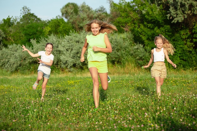 Kids, children running on meadow in summer's sunlight