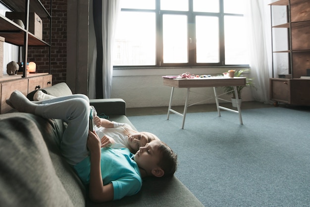 Free photo kids chilling on couch with tablet