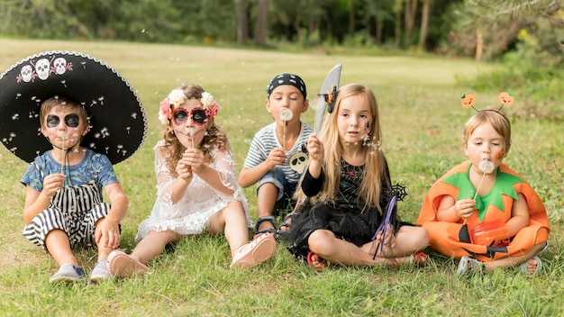 草の上に座ってハロウィンの衣装を着た子供たち