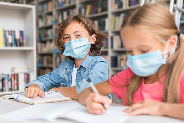 의료 마스크를 착용하는 동안 숙제를하는 아이들