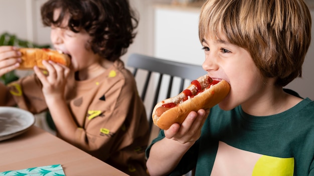 Дети вместе едят хот-доги