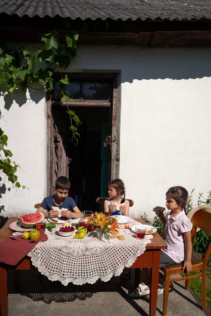 屋外のテーブルで一緒に食事をする子供たち