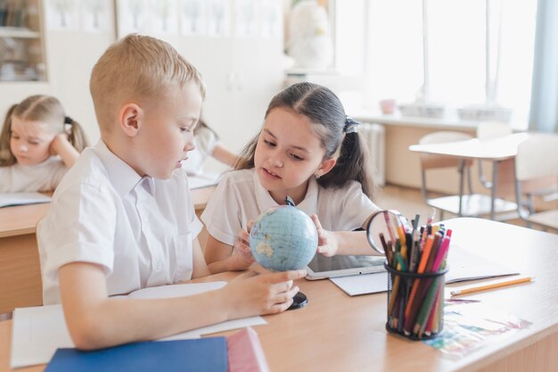 Bambini che esaminano il globo a lezione