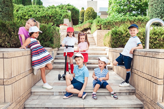 Free photo kids fashion concept. group of teen boys and girls posing at park. children colorful clothes, lifestyle, trendy colors concepts.