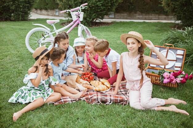 子供のファッションのコンセプトです。公園で緑の芝生に座っている10代の男の子と女の子のグループ。