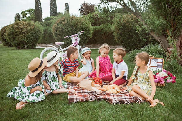 키즈 패션 개념. 공원에서 푸른 잔디에 앉아 십 대 소년과 소녀의 그룹