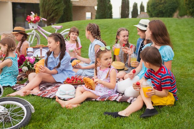 Kids fashion concept. group of teen girls sitting at green grass at park. Children colorful clothes, lifestyle, trendy colors concepts.