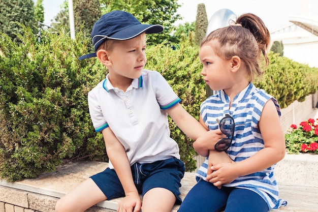 Kids fashion concept. teen boy and girl sitting at park. Children colorful clothes, lifestyle, trendy colors concepts.