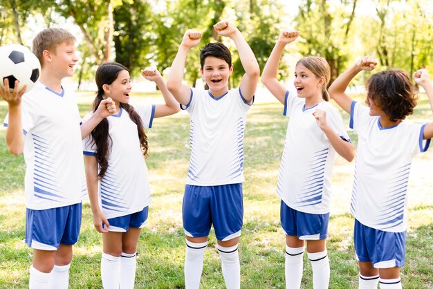 Kids in football equipment looking victorious after a match