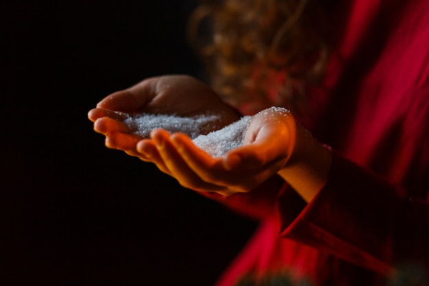 Kids hands holding christmas snow. Winter concept on black background.